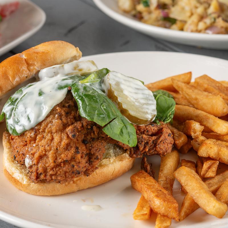 Fried chicken sandwich with pickles, fresh spinach and fries