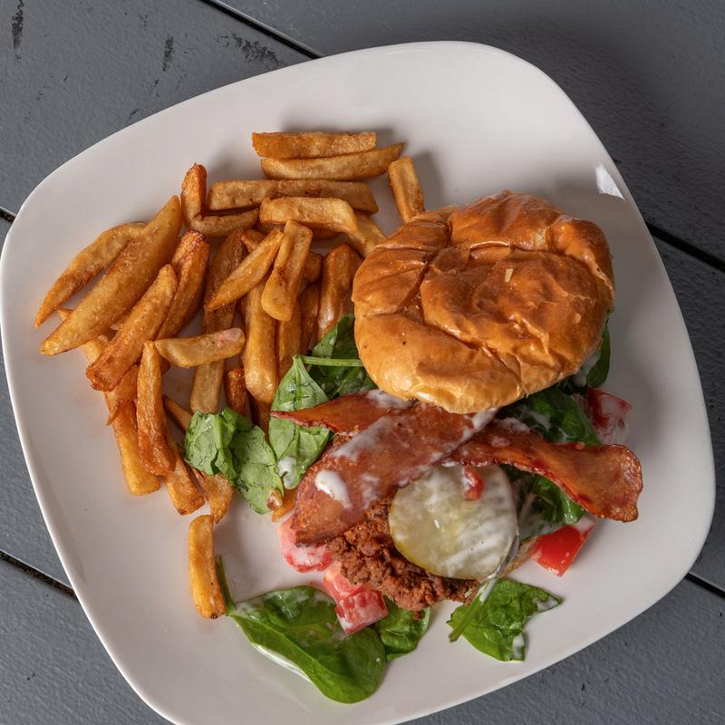 Crispy chicken sandwich with bacon, pickles and spinach, served with fries