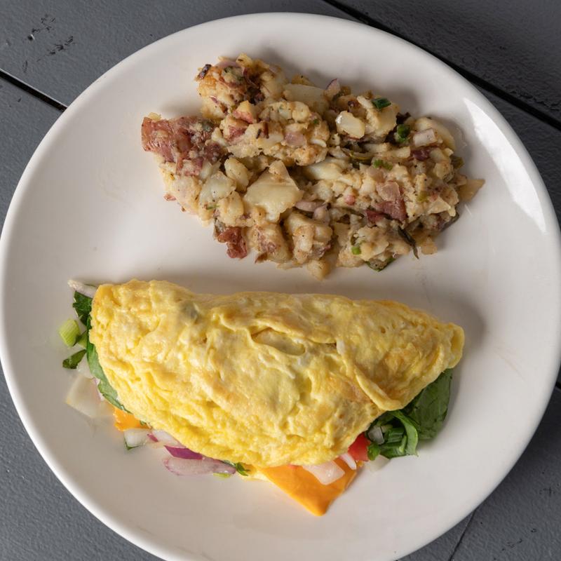 Omelet filled with vegetables and cheese, served with breakfast potatoes