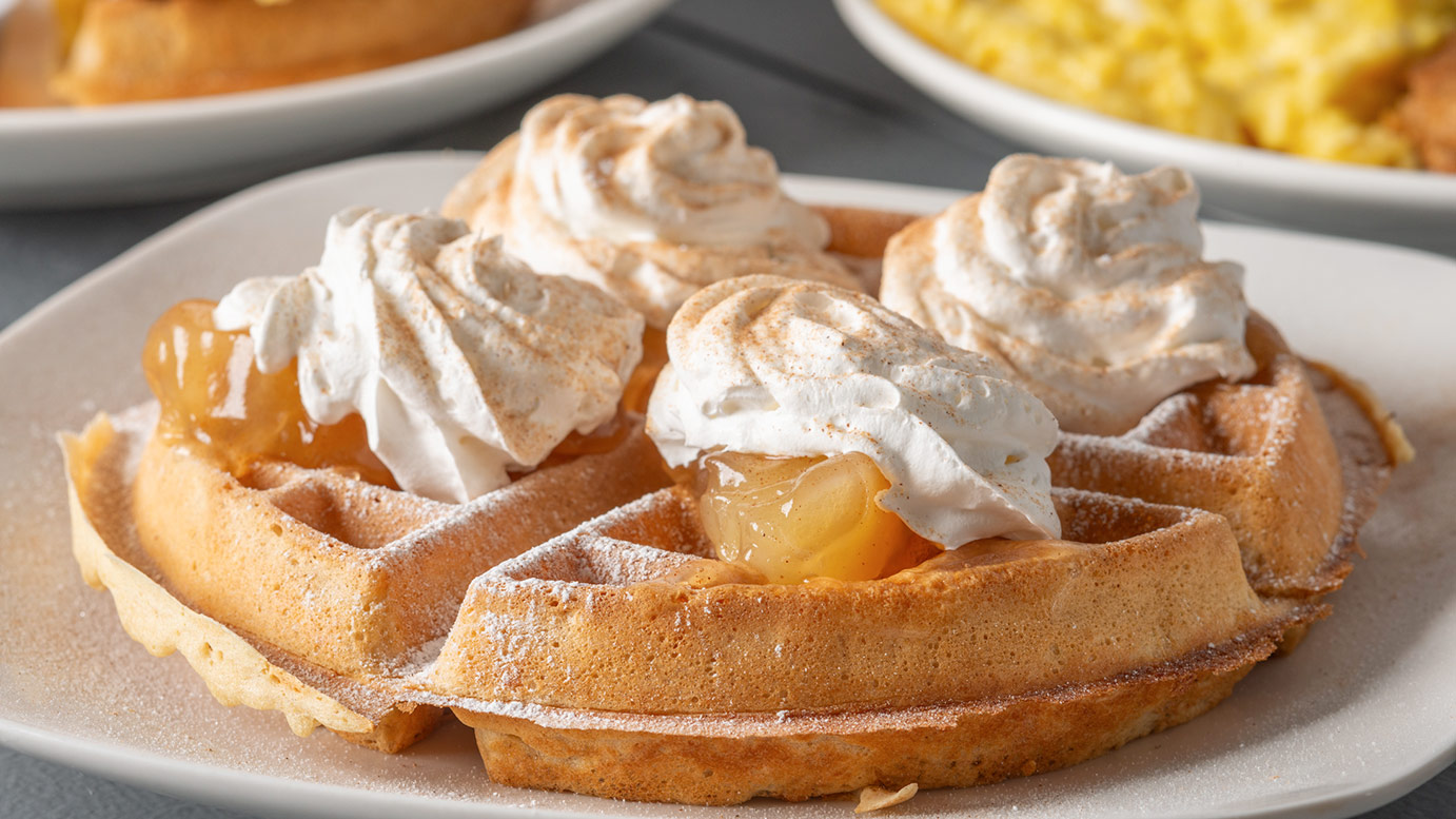 Apple cinnamon waffles topped with whipped cream and cinnamon