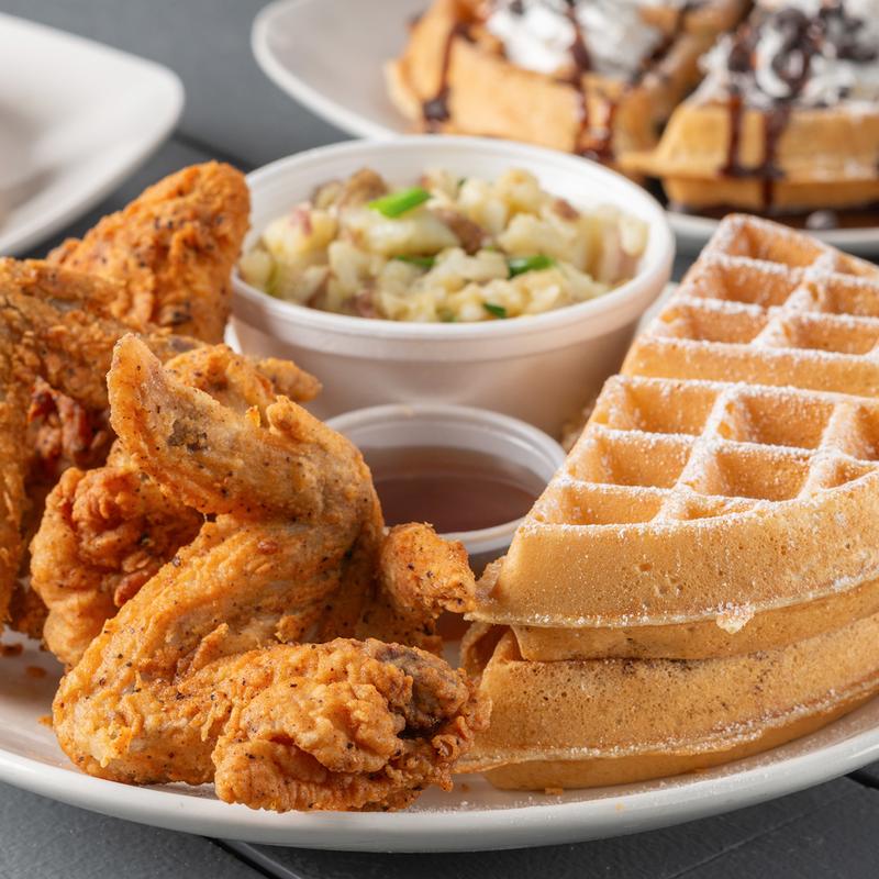 Chicken wings with waffles, potato salad and a small cup of syrup