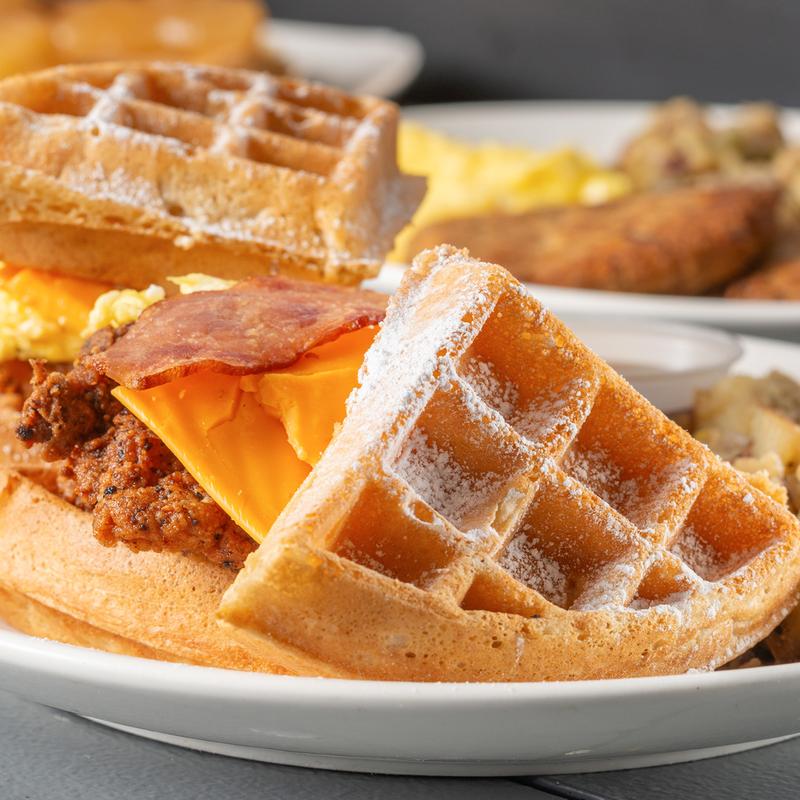 Fried chicken waffle sandwich with scrambled eggs, cheese and bacon