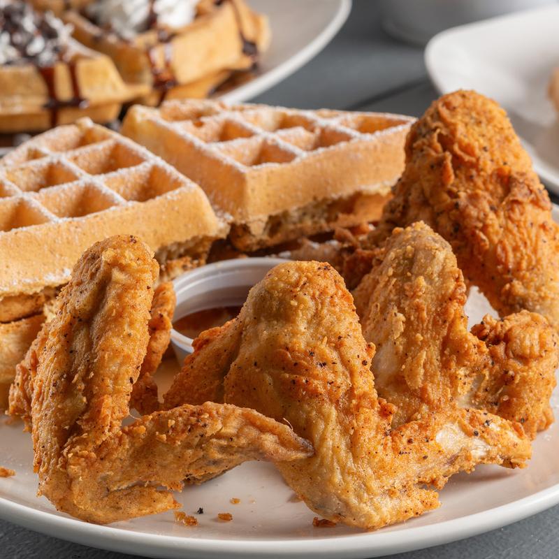 Crispy chicken wings served with waffles and syrup